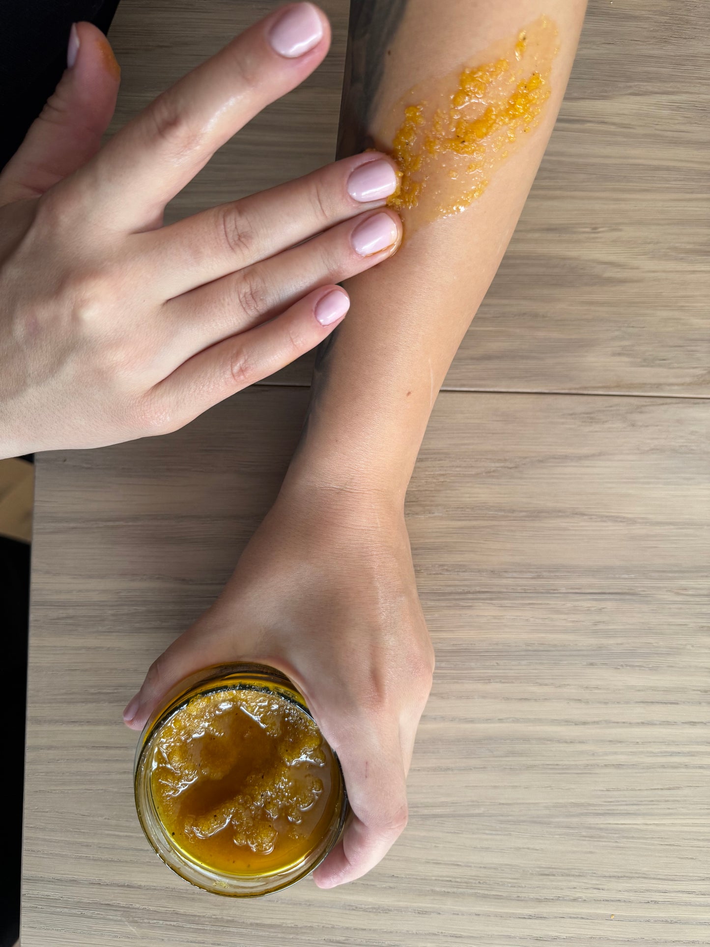 Aplikacja peelingu do ciała propolisowego Apimel z woskiem pszczelim na skórę przedramienia naturalna pielęgnacja i złuszczanie