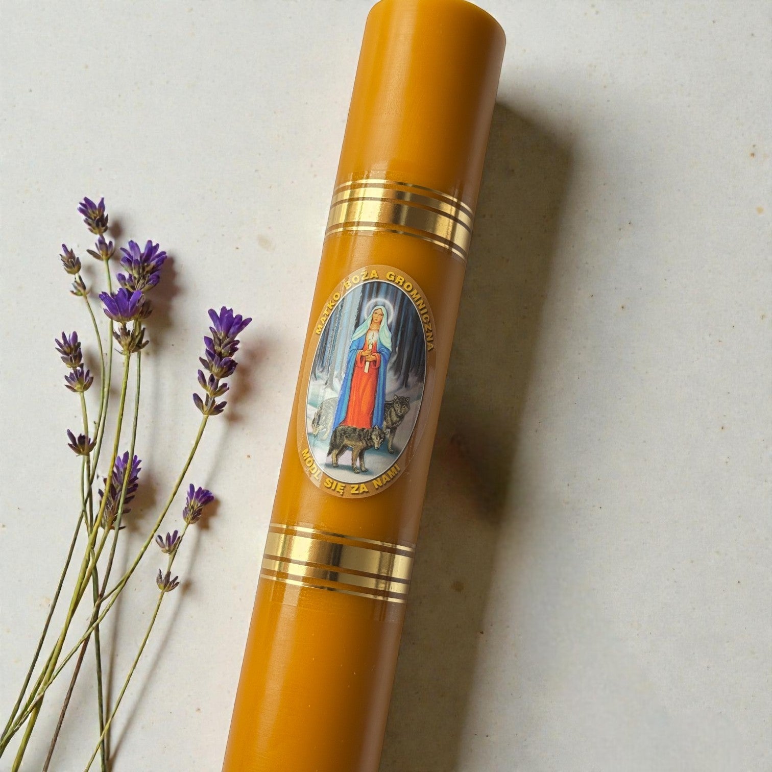 Gromnica z wosku pszczelego z wizerunkiem Matki Boskiej i złotymi zdobieniami obok gałązek lawendy